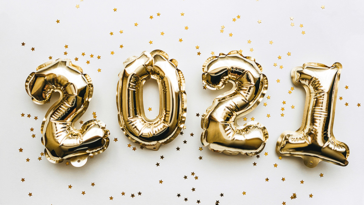 Golden inflatable holiday numbers 2021 on white background with golden confetti Christmas or New Year concept background.