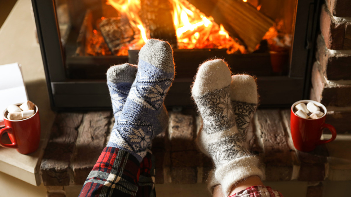 Couple in pajamas resting near fireplace indoors, closeup. Winter vacation